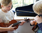 Zwei Kinder probieren den Klang von Violinen aus